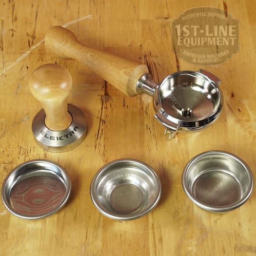 A wooden-handled espresso tamper, portafilter, and three metal filter baskets rest on wood beside the LIKE NEW - Elektra Verve Dual Boiler Espresso Machine (C104), with the 1st-Line Equipment logo in the upper right corner. © 2025 1st-line.com