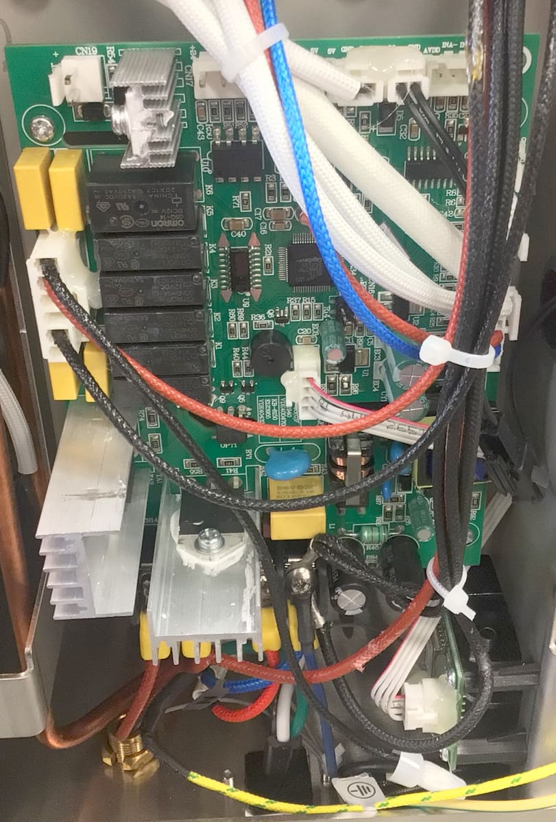 Close-up of a Bellezza Inizio mother board inside an electronic device, featuring various wires, connectors, relays, and electronic components, with multiple colored cables tied and routed across the board. © 2025 1st-line.com