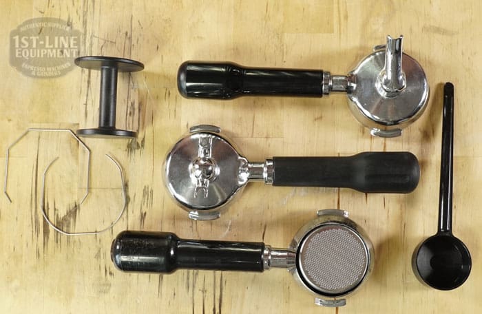 Three espresso portafilters with black handles, a tamper, metal clip, and black scoop are neatly displayed—perfect accessories for your SOLD SIDEWALK SALE - Fiorenzato Bricoletta Electronic Direct Connect HX Espresso Machine (E011). © 2025 1st-line.com