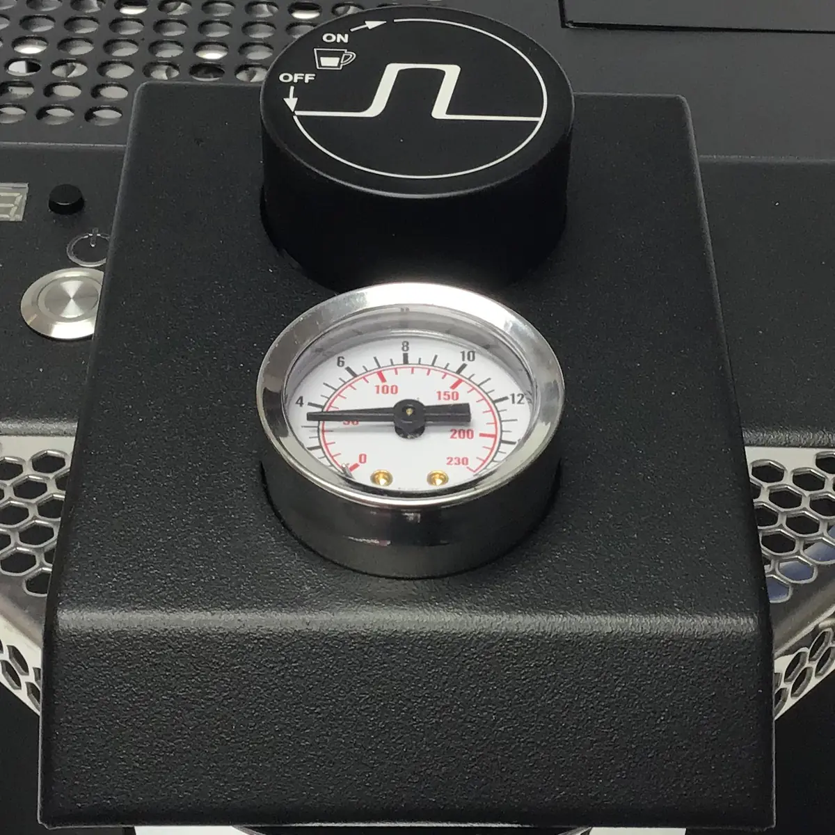 A close-up of a pressure gauge on the Nurri R-Type DB Espresso Machine shows a silver rim up to 230. Above it, a black dial with a white power symbol marked ON and OFF is set on a control panel featuring metal mesh details. © 2025 1st-line.com
