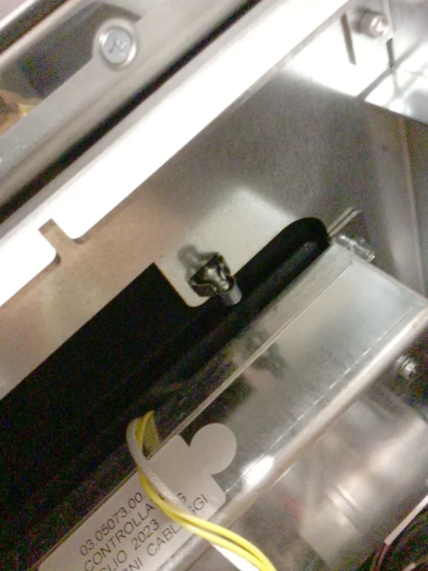 Close-up of a metallic surface on the Carimali Bubble with a small screw lodged in a black groove, some yellow and white wiring visible, and part of a label reading Swap Triac in the lower left corner. © 2025 1st-line.com