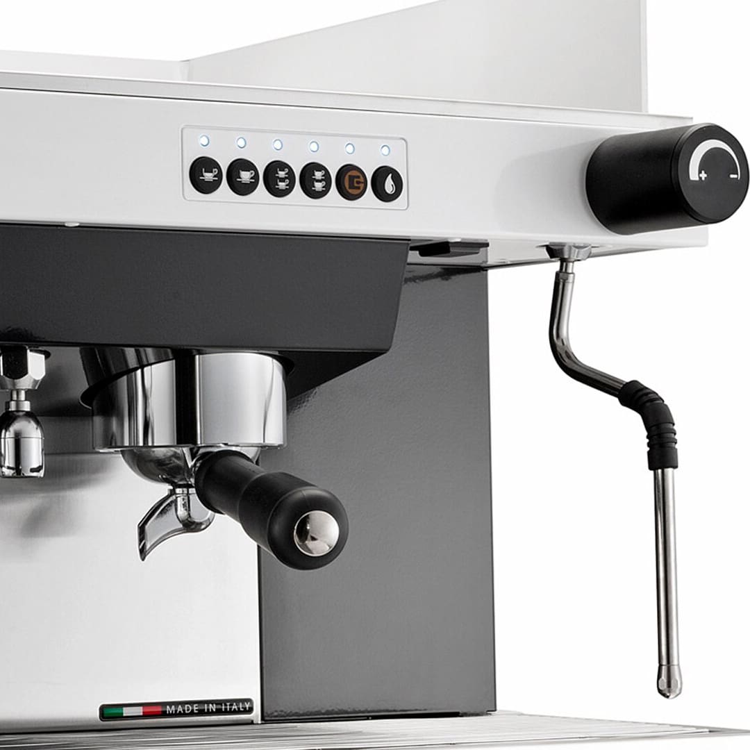 Close-up of a modern espresso machine with control buttons, a portafilter handle, steam wand, and a Made in Italy label on the lower front. The machine is white and black with a sleek, professional design. © 2025 1st-line.com