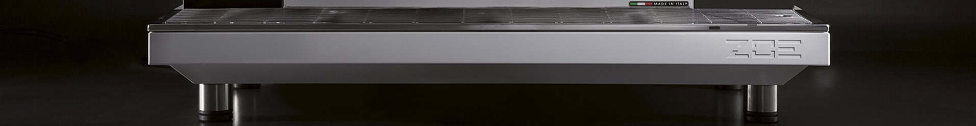 Front view of the Sanremo Zoe Tall Competition 2 Group Commercial Espresso Machine on a dark background, highlighting its stainless steel build, metal legs, sleek design, and EOS initials embossed on the front panel. © 2025 1st-line.com