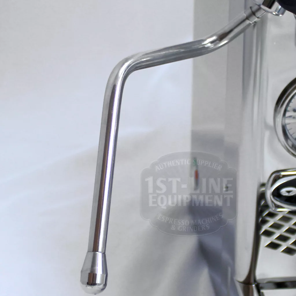 Close-up view of a stainless steel steam wand attached to an espresso machine, with a thermometer and drip tray partially visible in the background. © 2025 1st-line.com