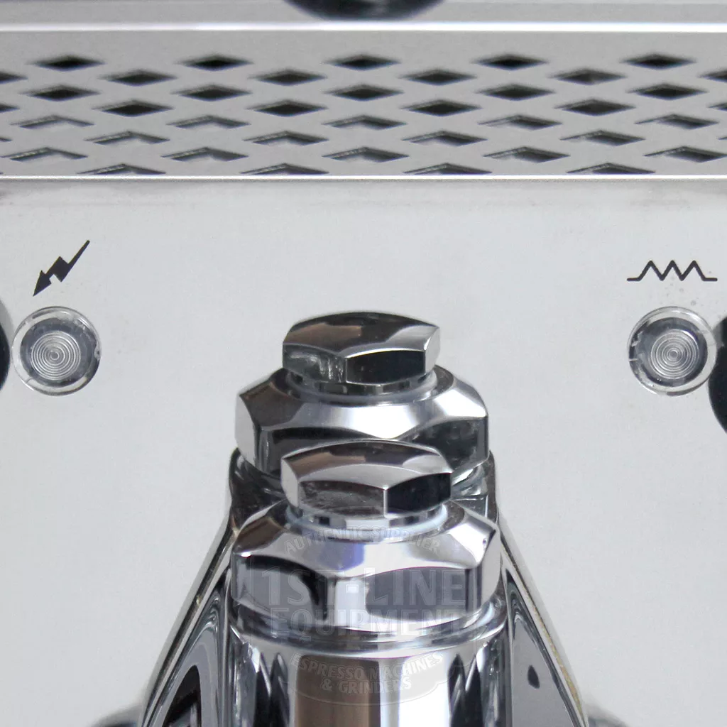 Close-up of a shiny metal espresso machine with a perforated tray above and two buttons, each marked with a different symbol, on either side of a central knob. © 2025 1st-line.com