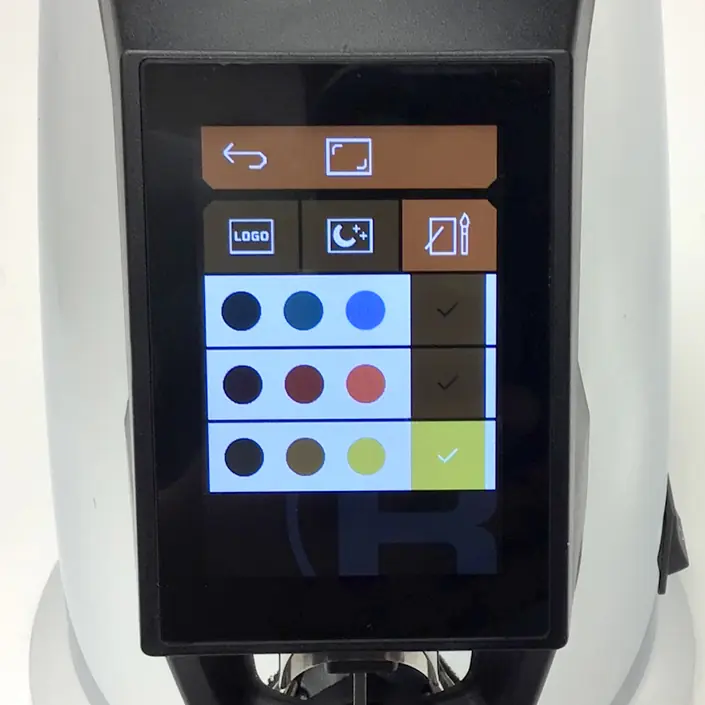 A touchscreen display shows a color selection menu with three rows of colored circles—blue, red, brown, yellow—each row has a checkmark on the right. Navigation, logo, and edit icons appear at the top. © 2025 1st-line.com