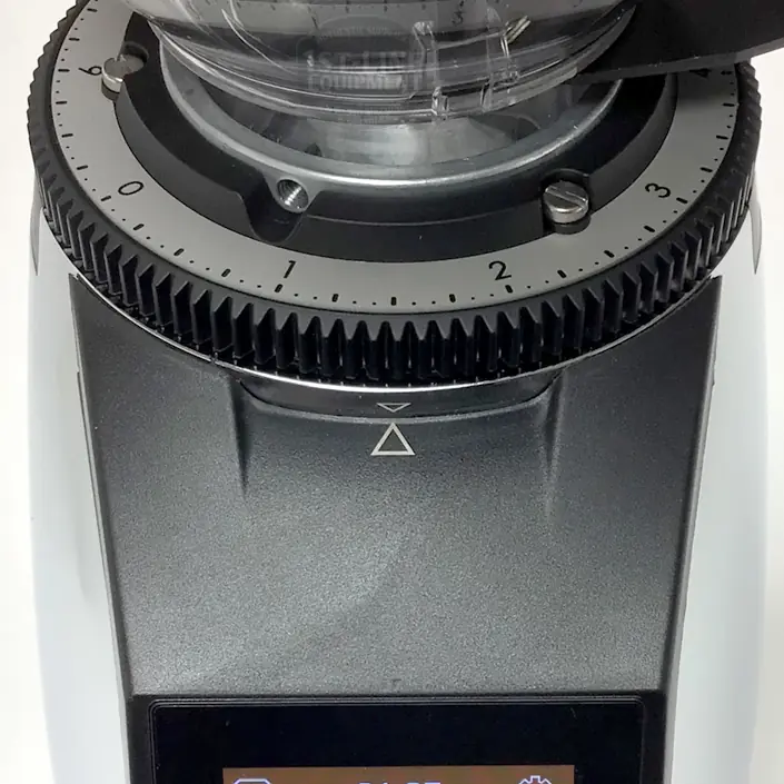 Close-up of the top of a coffee grinder with a numbered dial for adjusting grind size, a clear hopper, and a display screen at the bottom. The dial is set between 2 and 3. © 2025 1st-line.com