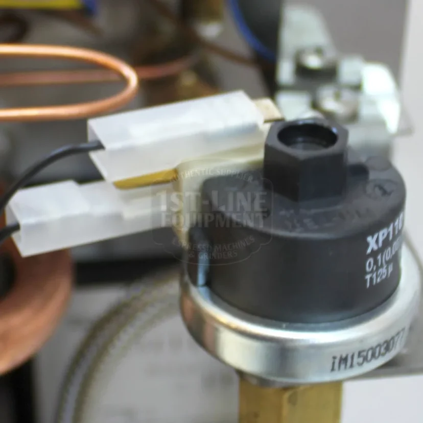 Close-up of electrical connectors attached to a black cylindrical XP110 component with a metal base, surrounded by copper tubing and other mechanical parts. © 2025 1st-line.com