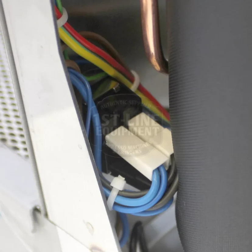 Close-up view of wires in various colors (red, yellow, green, blue, black, and brown) connected inside a metal electrical or appliance compartment. Some components and tubing are also visible. © 2025 1st-line.com