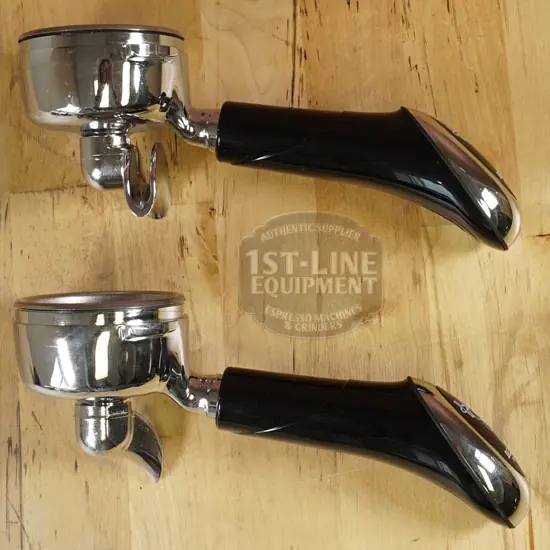 Two espresso machine portafilters with black handles are placed on a wooden surface, positioned parallel to each other with handles facing right and filter baskets facing left. © 2025 1st-line.com