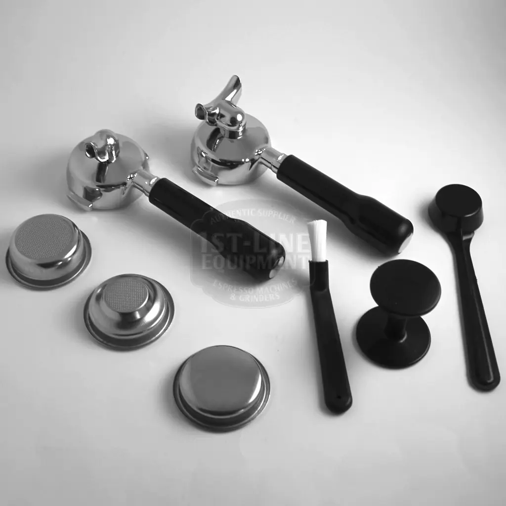 Two espresso portafilters with black handles, metal filter baskets, a brush, a tamper, and a dosing tool arranged on a white surface. The items are organized for coffee preparation. © 2025 1st-line.com