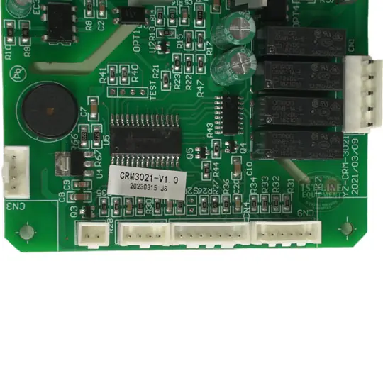 A green printed circuit board (PCB) with multiple electronic components, including black relays, white connectors, a round black component, integrated circuits, and a white label marked “CRM3021-V1.0”. © 2025 1st-line.com