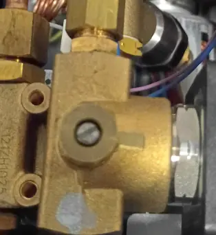 Close-up of an Elektra EVOK internal valve with several pipes and fittings attached, including copper tubing and hexagonal connectors, against a background of wires and machine parts. 2025 1st-line.com