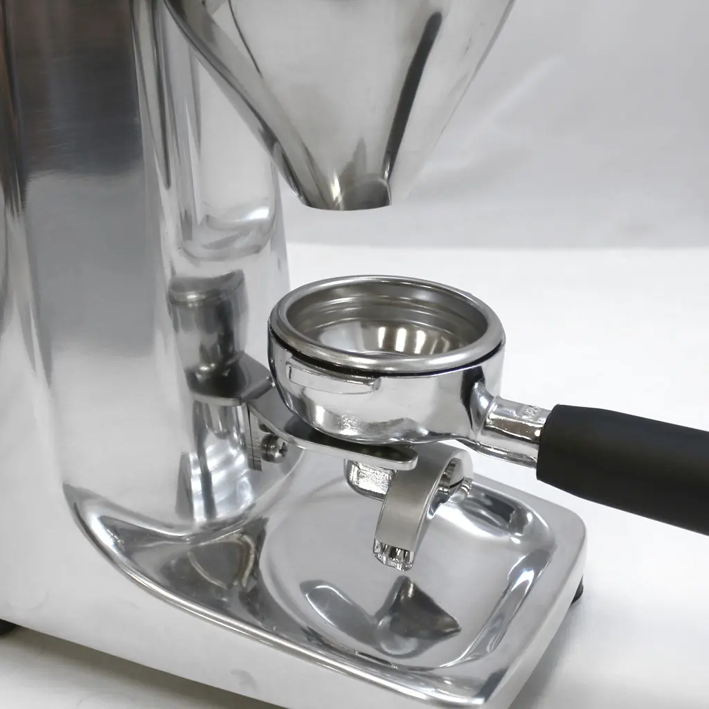 A close-up of a shiny Q50 espresso grinder with a portafilter positioned beneath the chute, ready to collect freshly ground coffee. The equipment has a sleek, metallic finish and a black handle—perfect for removing the fork with ease. 2025 1st-line.com