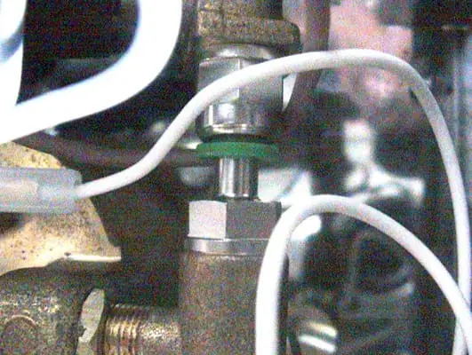 A close-up view of a metal solenoid valve or connector with white wires and tubing attached, likely part of industrial or Lelit PL41 espresso machine equipment. The background is blurred, highlighting the Anna hardware components. 2025 1st-line.com