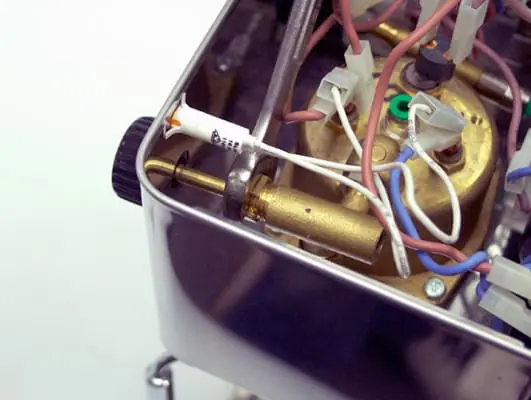 A close-up of the internal components of a Lelit PL41 Anna coffee machine, showing wires, connectors, a brass boiler, steam valve repair parts, and various electronic components inside a metal casing. 2025 1st-line.com