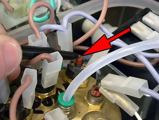 A close-up of a hand using a tool to press the Thermostat Reset button on a Lelit PL41 electrical component, indicated by a red arrow, among several wires and connectors. 2025 1st-line.com