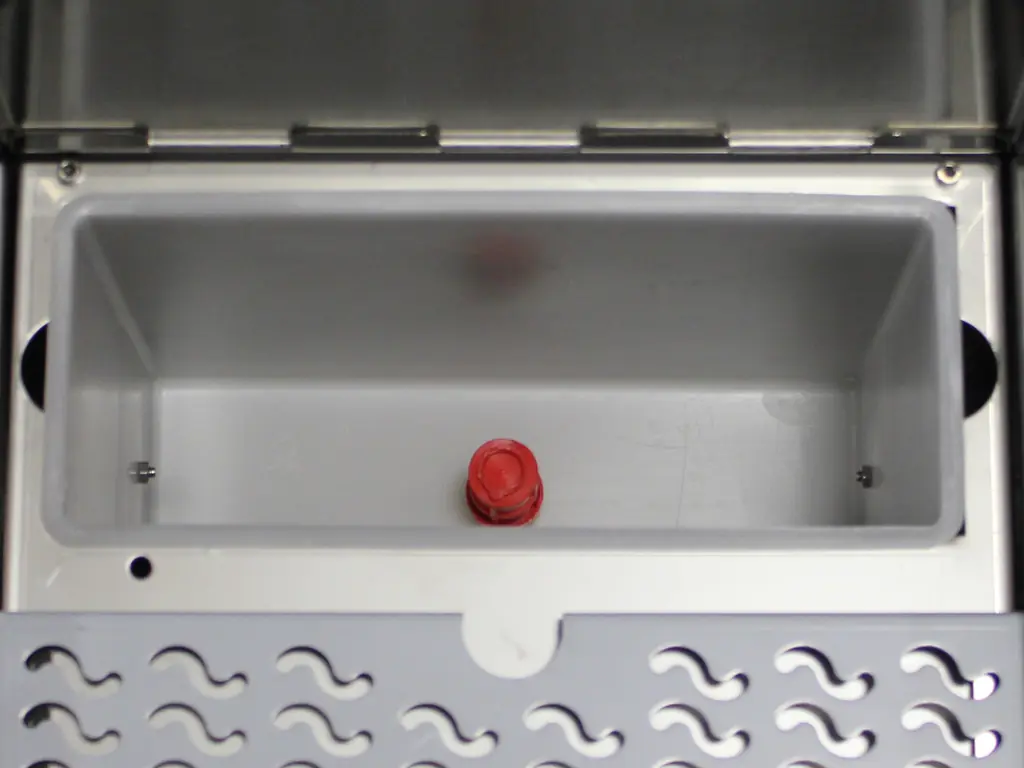A rectangular metal compartment with a single red knob in the center at the bottom, viewed from above. The bottom edge features a patterned metal plate with holes, suggesting compatibility for Strega switchable or Tank to Direct Connect Conversion setups. 2025 1st-line.com