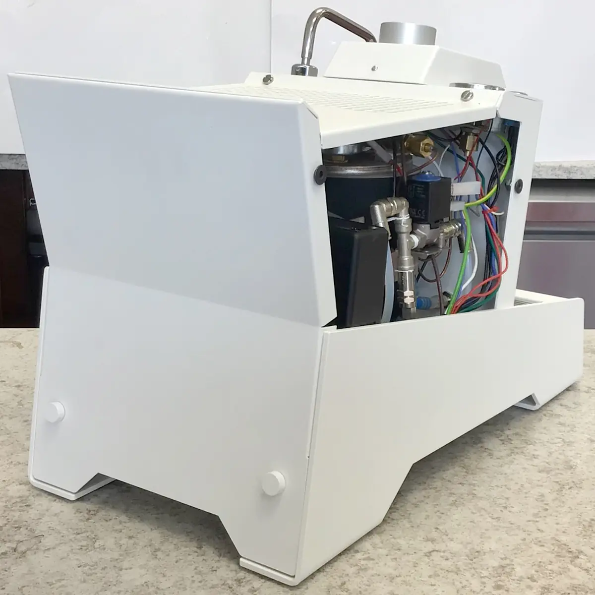 The SIDEWALK SALE Nurri R-TYPE SB (HX) Espresso Machine (RETURNED & REFURBISHED), in white, sits on a countertop partially open, revealing internal wires and tubes, indicating it is a refurbished unit. 2025 1st-line.com