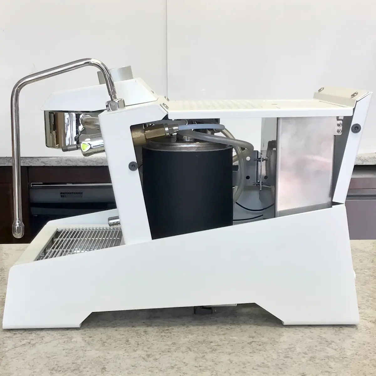 A side view of the SIDEWALK SALE Nurri R-TYPE SB (HX) Espresso Machine (RETURNED & REFURBISHED) in modern white, featuring a steam wand, metal portafilter, and black water reservoir on a light countertop. 2025 1st-line.com