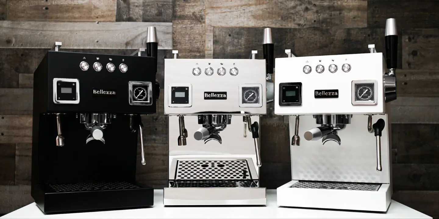 Three Bellezza espresso machines in black, silver, and white are lined up on a white counter with a rustic wooden background. Each features a digital display, control buttons, and steam wands—perfect for your Early Black Friday upgrade.