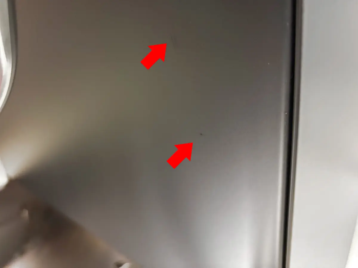A close-up of a metallic surface with two small scratches indicated by red arrows. The smooth, reflective finish and minor imperfections are highlighted—perfect for detail inspection ahead of the Early Black Friday Sale.