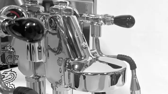 Close-up of the polished Bezzera Luce HX Espresso Machine, featuring shiny chrome with handles and levers, reflecting its surroundings and set against a plain white background.