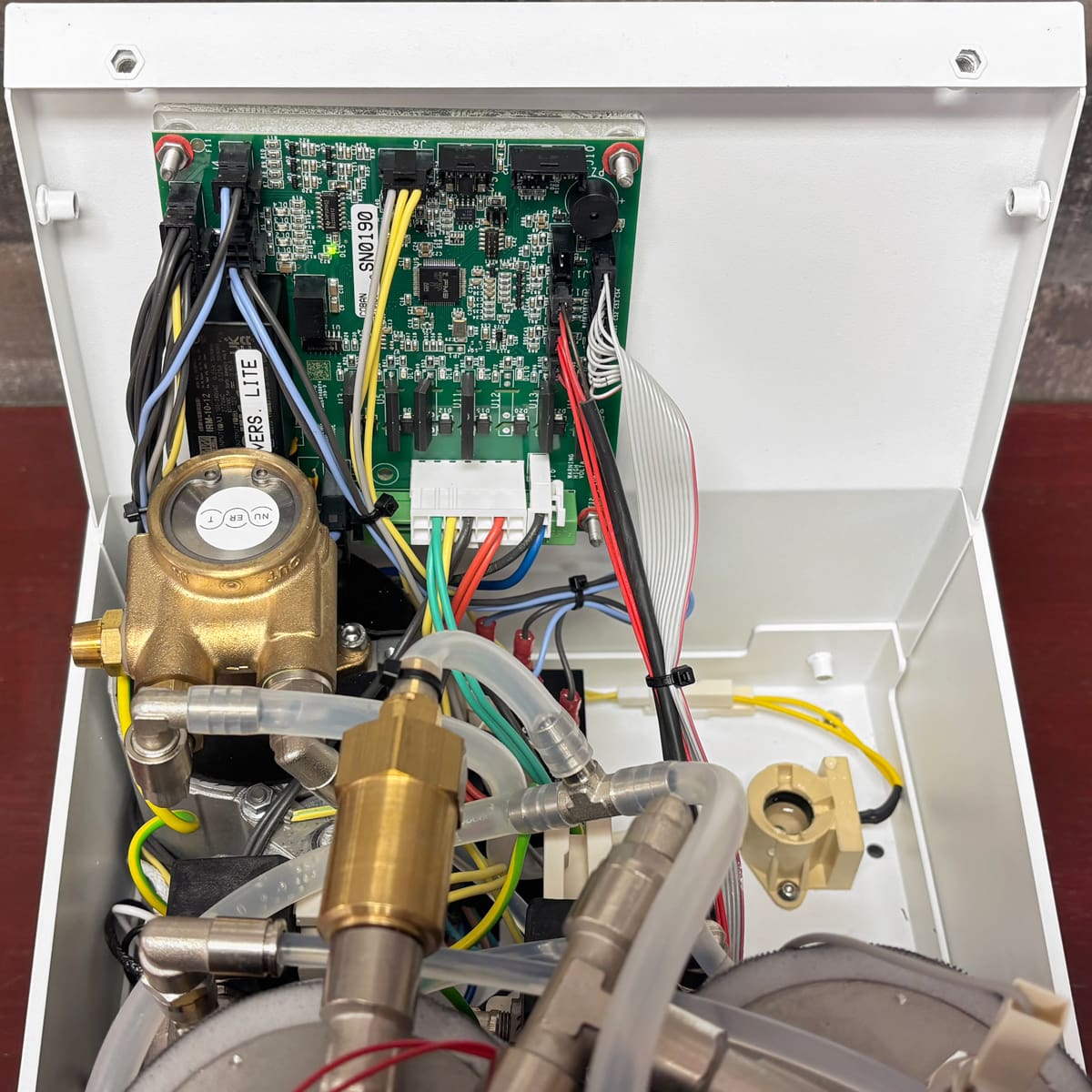 The Nurri R-Type DB Dual Boiler Espresso Machine, shown open with a green circuit board, wires, valves, and tubes inside a white metal casing, features an advanced dual boiler system.