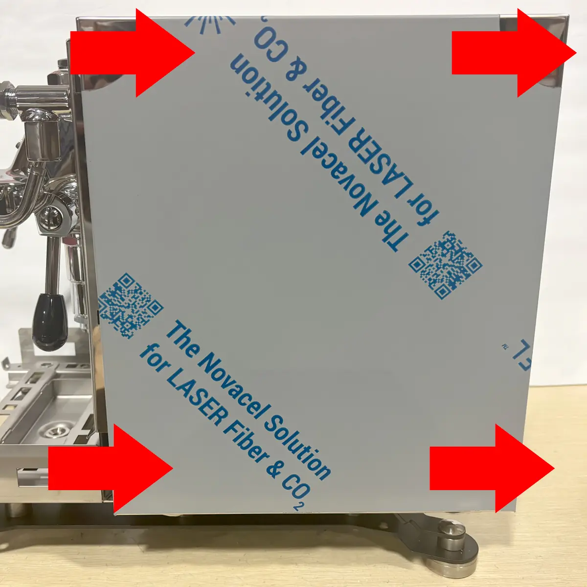 A metal panel with protective film, partially attached to an espresso machine&mdash;possibly a Bezzera Sole&mdash;is outlined by four large red arrows pointing at its edges. Text and QR codes are visible on the film, highlighting points of access.