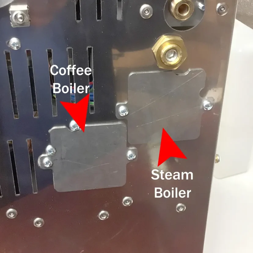Close-up of a Magister Stella machine panel with two labeled areas: one marked Coffee Boiler and another marked Steam Boiler, each indicated by a red arrow pointing to a metal plate, emphasizing steam and hot water controls.