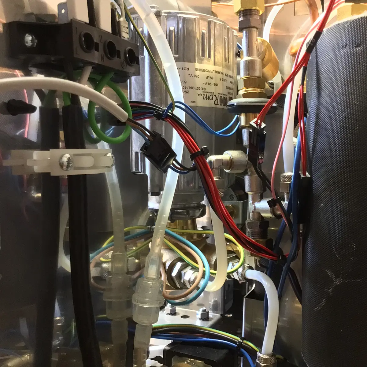 Close-up view inside a Magister Stella machine, revealing colorful wires, tubes, valves, and metal components that suggest a complex electrical or mechanical system.